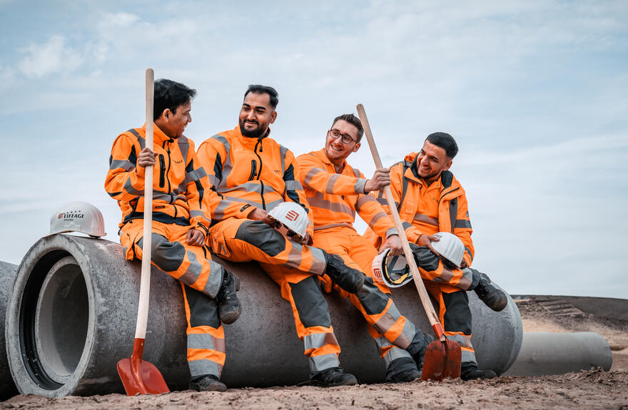 Vier Azubis der Eiffage Infra-Bau sitzen auf einem Betonteil.